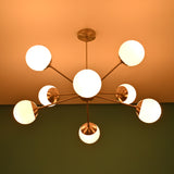 Mid century brass chandelier casting soft ceiling glow with opal glass globe shades