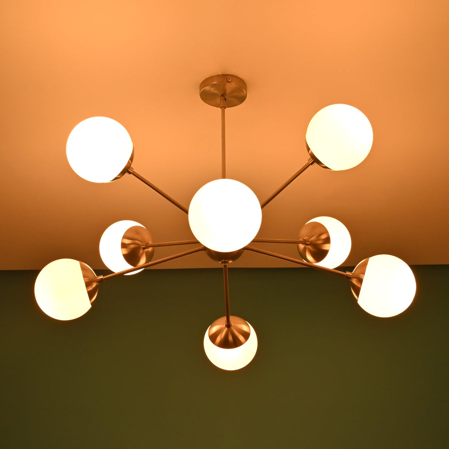 Modern 8 light brass globe chandelier with opal glass shades and balanced mid century silhouette