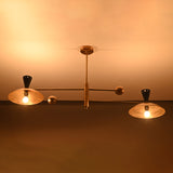 Evening view of mid-century Diabolo brass chandelier glowing warmly with sculpted brass shades and minimal linear arms.