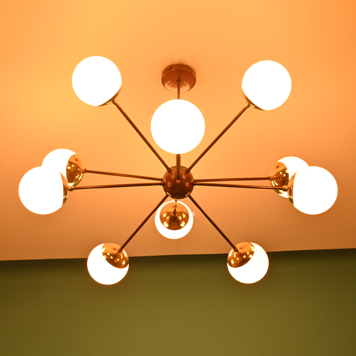 Mid century modern brass globe chandelier casting soft, warm light for elegant residential and hospitality interiors.