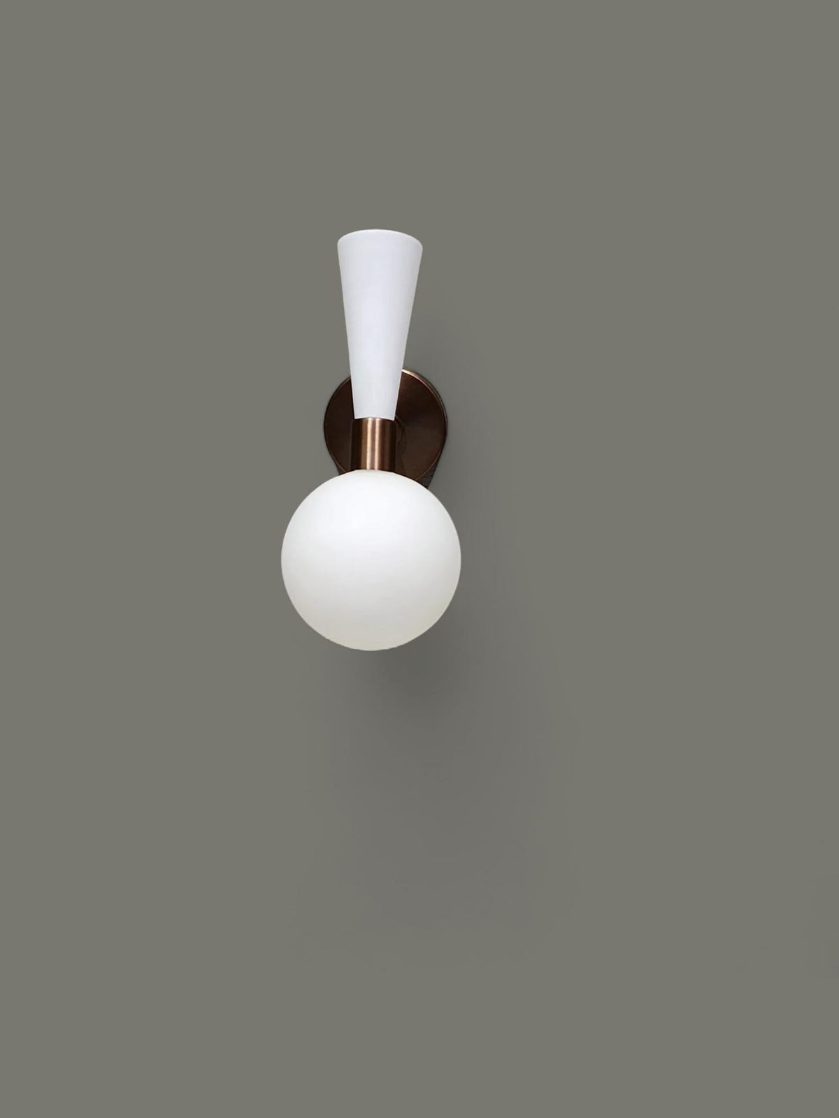 Front view of mid-century style brass and white wall light with frosted glass globe shade