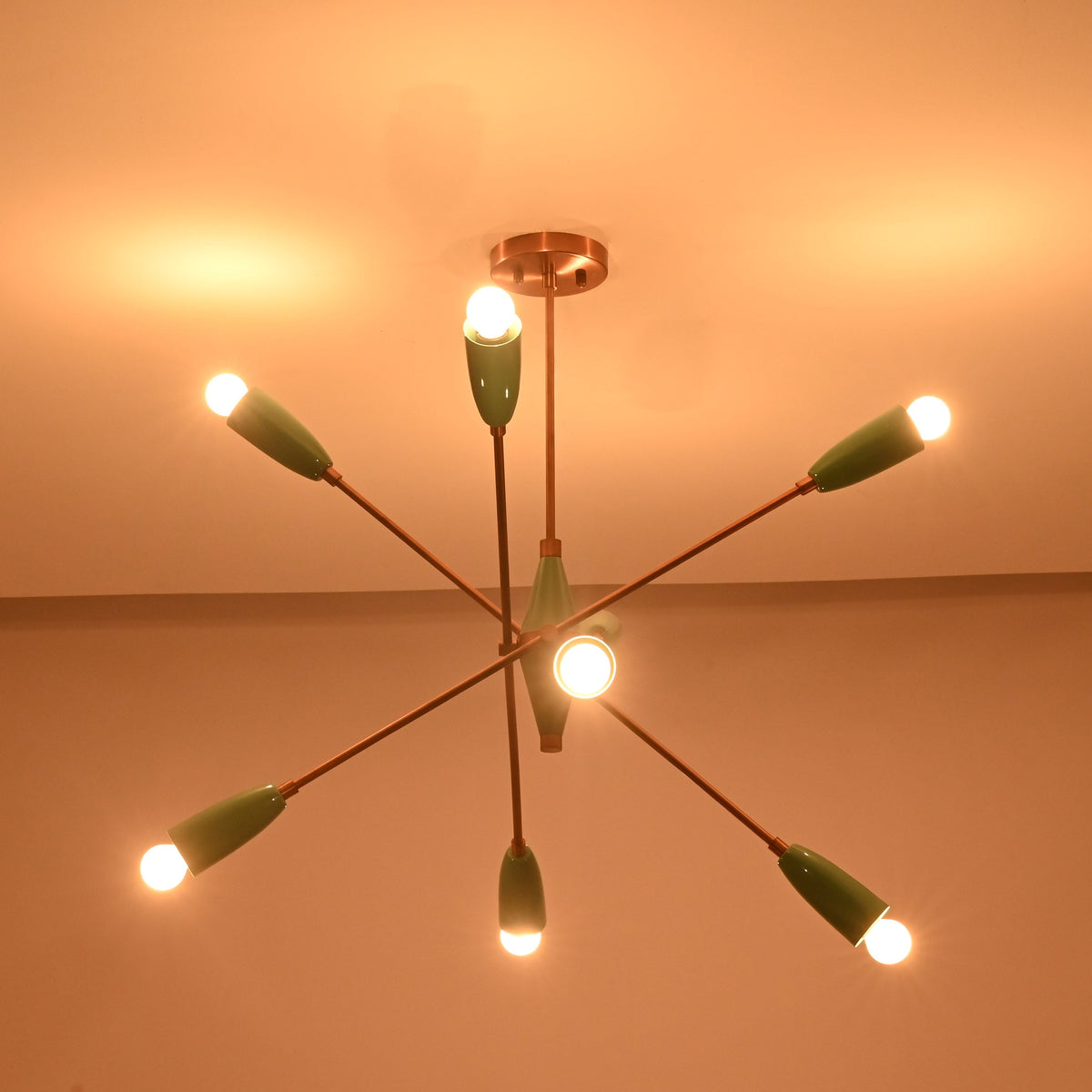 Mid century style sputnik chandelier in mint green finish with brass structure and warm glowing bulbs.