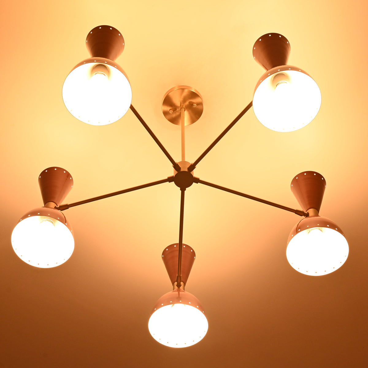 Mid-century style peach and brass ceiling chandelier beautifully lit with warm bulbs