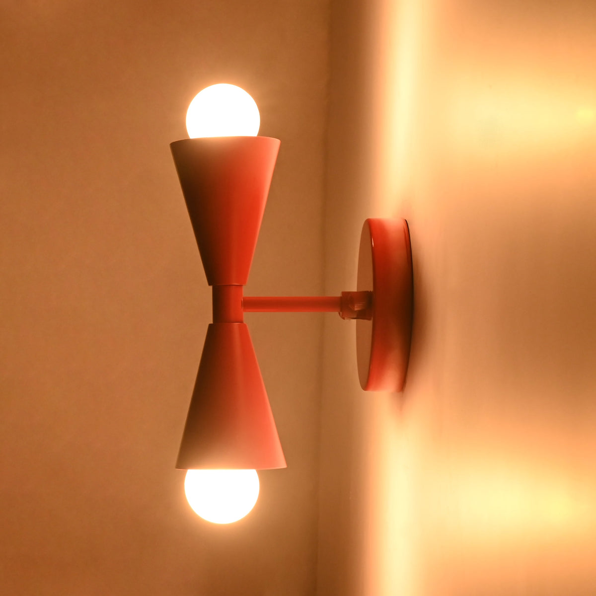 Side mounted Milan Modern Double Cone Wall Sconce installed on wall with warm ambient illumination