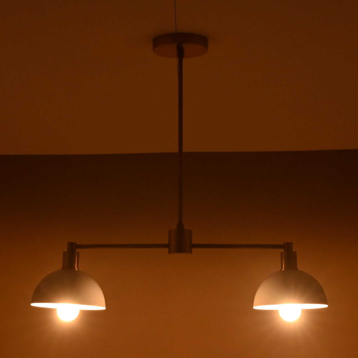 Modern brass pendant light with soft symmetrical glow from two domes
