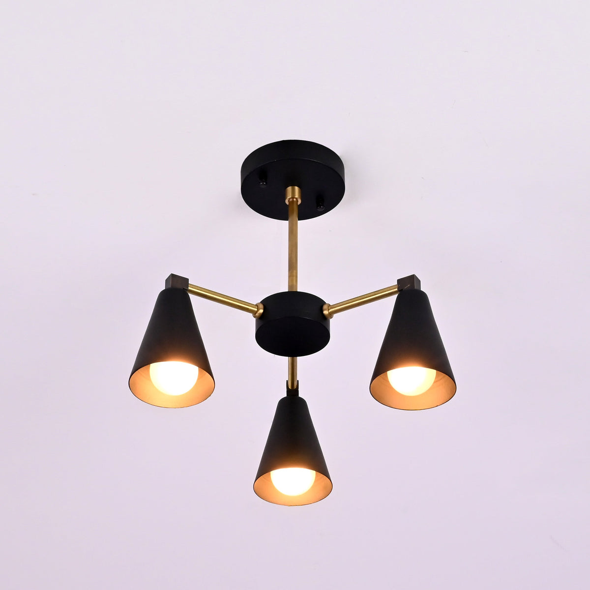 Front view of minimalist cone style brass chandelier with three lights and matte black accents