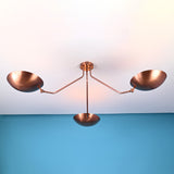 Minimalist industrial brass ceiling light featuring three bowl shaped shades designed for indirect ambient lighting