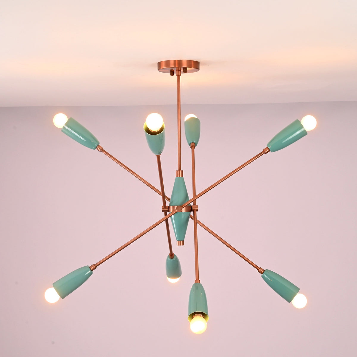 Bottom view of mint green brass chandelier highlighting radial arm layout and warm light distribution.