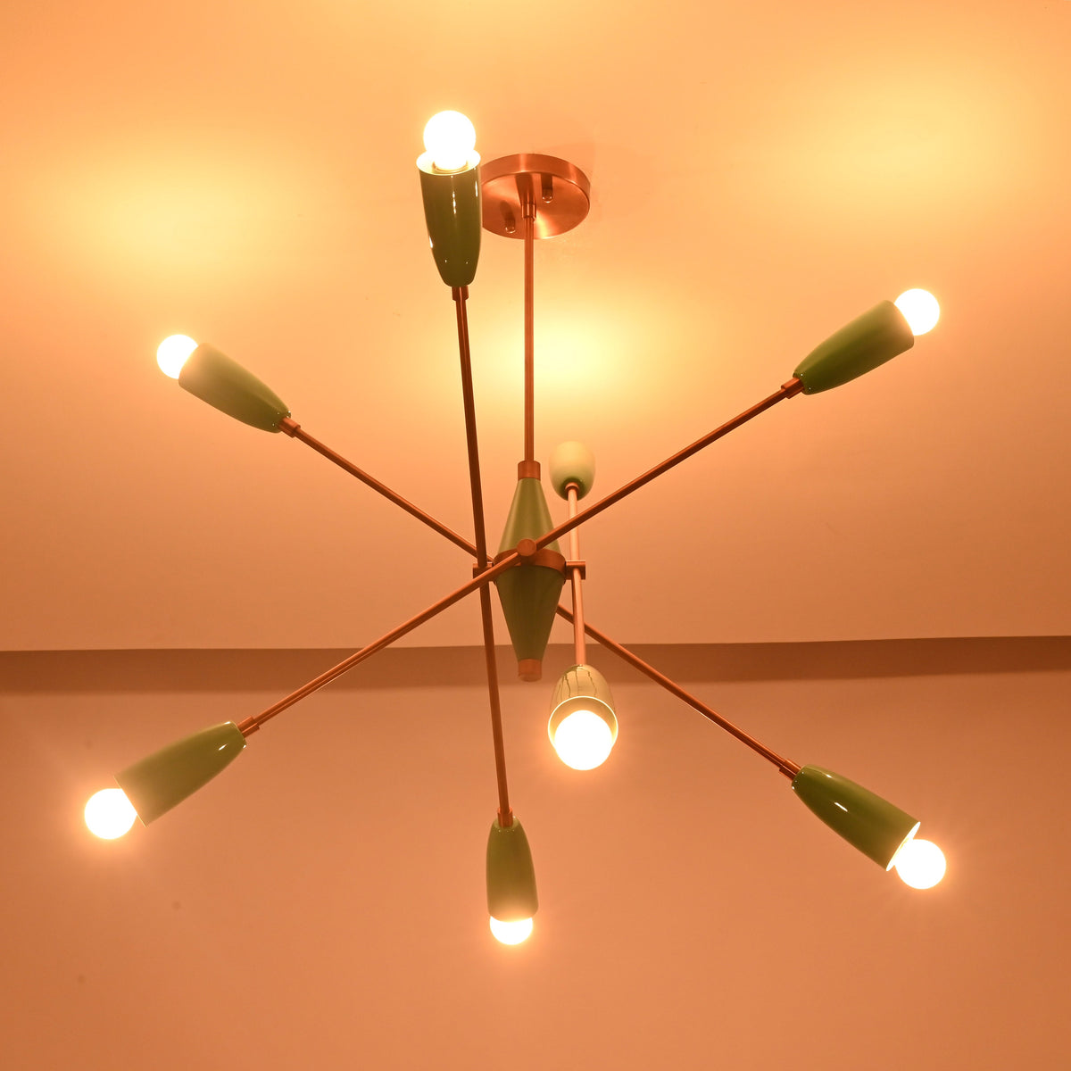 Mint green sputnik chandelier casting warm ambient light across the ceiling in a dark setting.