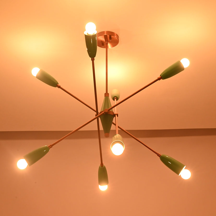 Front view of mint green 8 light sputnik ceiling light with brass arms and glowing bulbs.