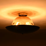Warm halo lighting effect around mixed-finish brass flushmount featuring polished brass dome and illuminated interior bulb.