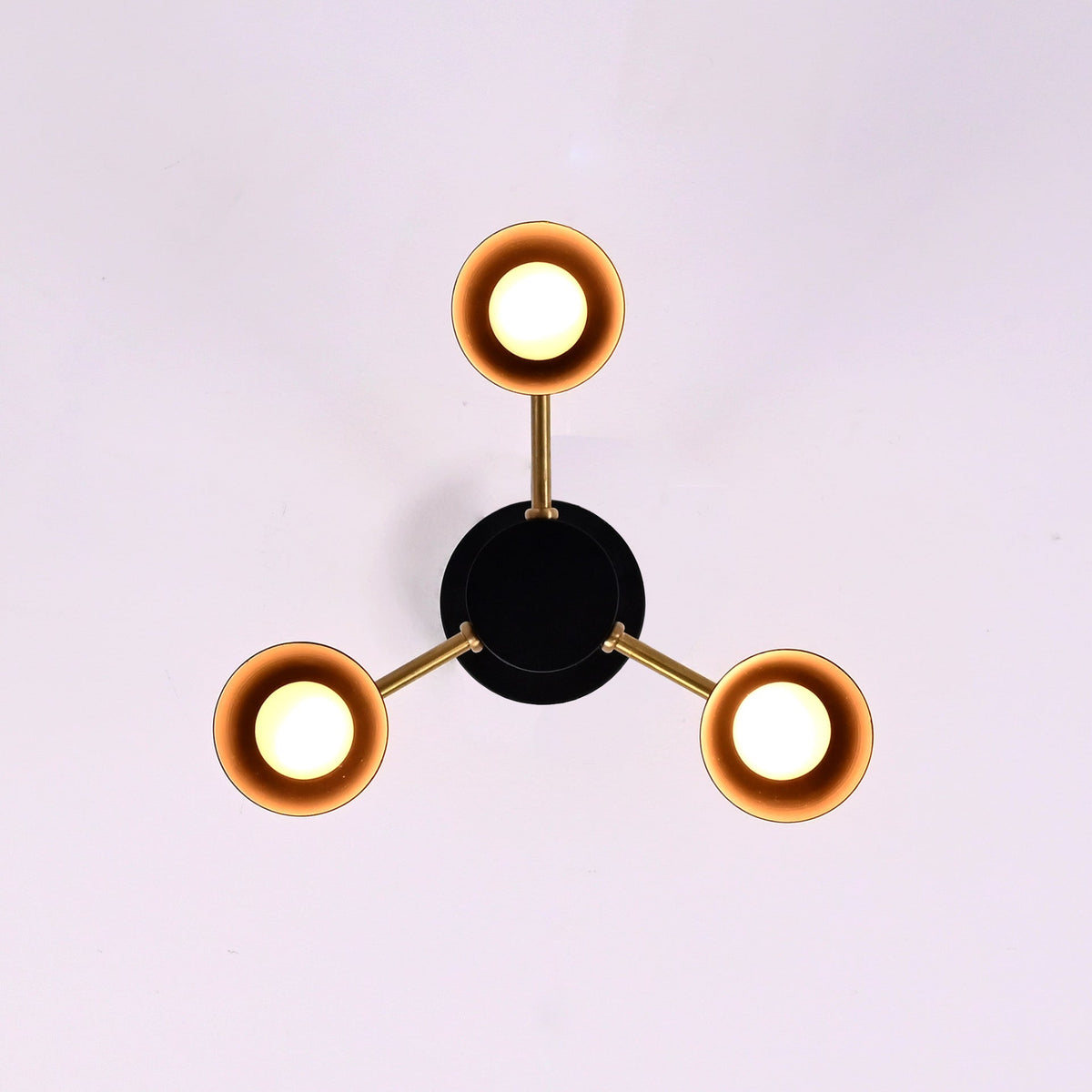 Top view of modern three light cone brass chandelier with warm ambient glow and minimalist design