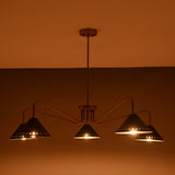 Night view of modern 5-light brass cone chandelier with perforated detailing and warm golden illumination.