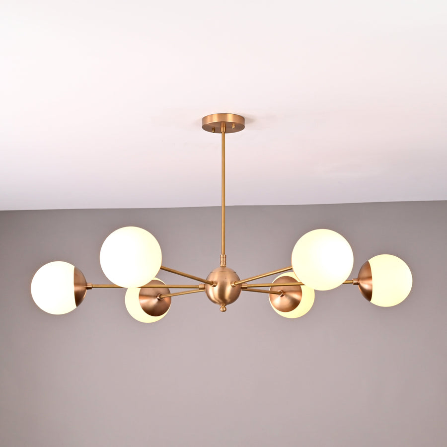 Handmade 6-globe brass chandelier featuring opal glass globes and brushed brass finish for modern interiors.