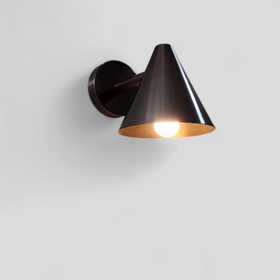 Handcrafted brushed antique brass cone wall light with minimalist design and warm metallic finish by Brass Leaf Studio.