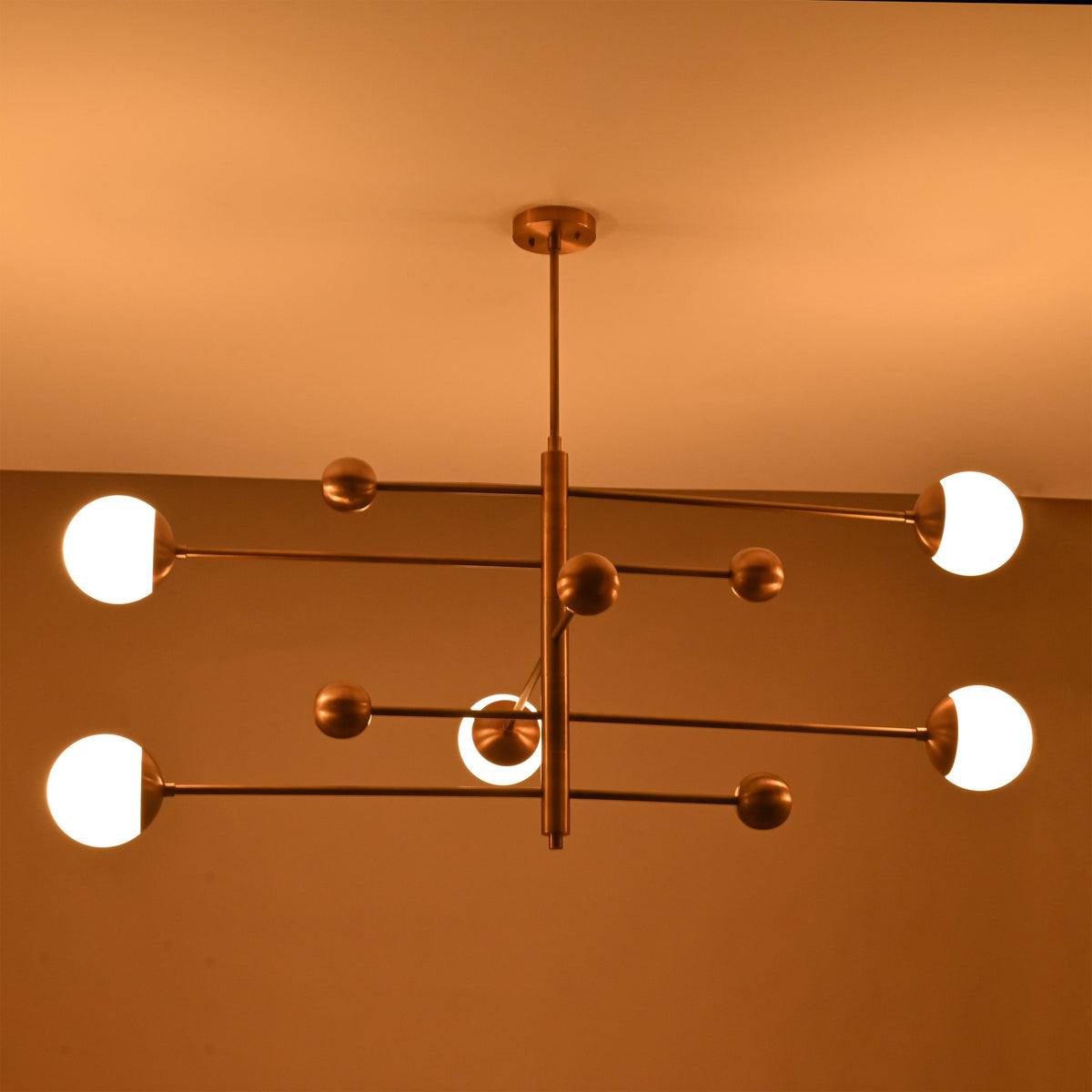 Modern bedroom globe ceiling light with five lights arranged on a clean architectural brass frame