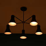 Modern brass 5 cone chandelier illuminated in dark room creating warm ambient lighting effect