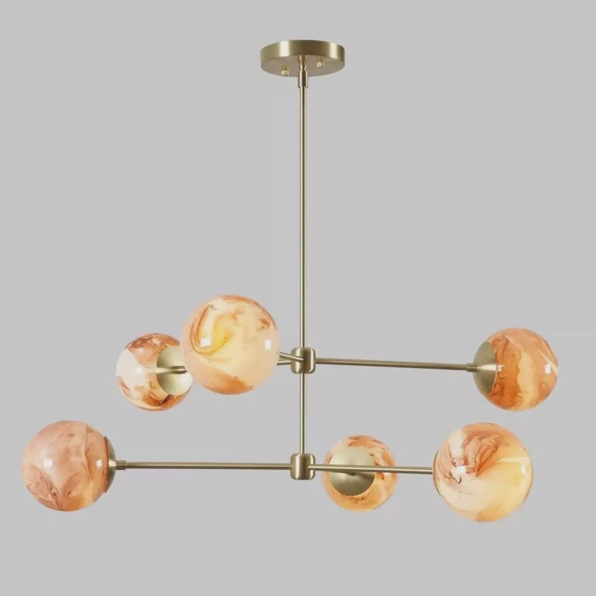 Modern 6-light brass chandelier with marble glass globe shades, featuring a sculptural radial design and warm ambient lighting by Brass Leaf Studio.