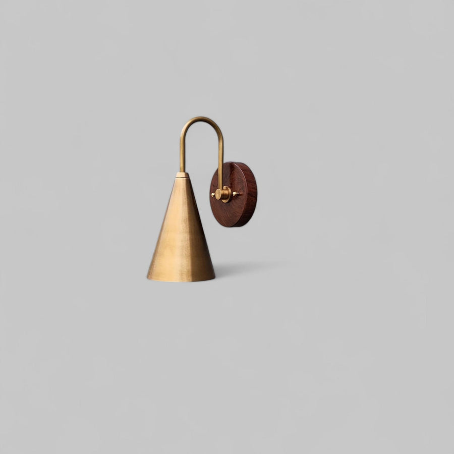 Side view of modern brass and wood wall sconce handcrafted by Brass Leaf Studio with cone-shaped brass shade and round wooden base.