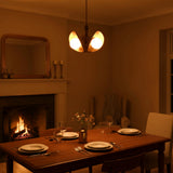 Modern brass bedroom chandelier with three opal glass globes creating a soft warm glow above a cozy bed setting