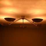 Modern brass ceiling light producing indirect upward glow through sculpted bowl-shaped shades.