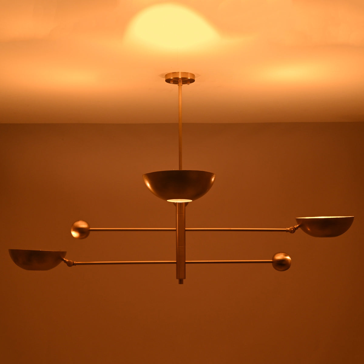Modern brass ceiling chandelier casting soft indirect glow across the ceiling