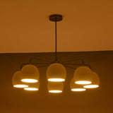 Minimalist 8-light chandelier in brass with soft evening light illuminating ivory dome shades.
