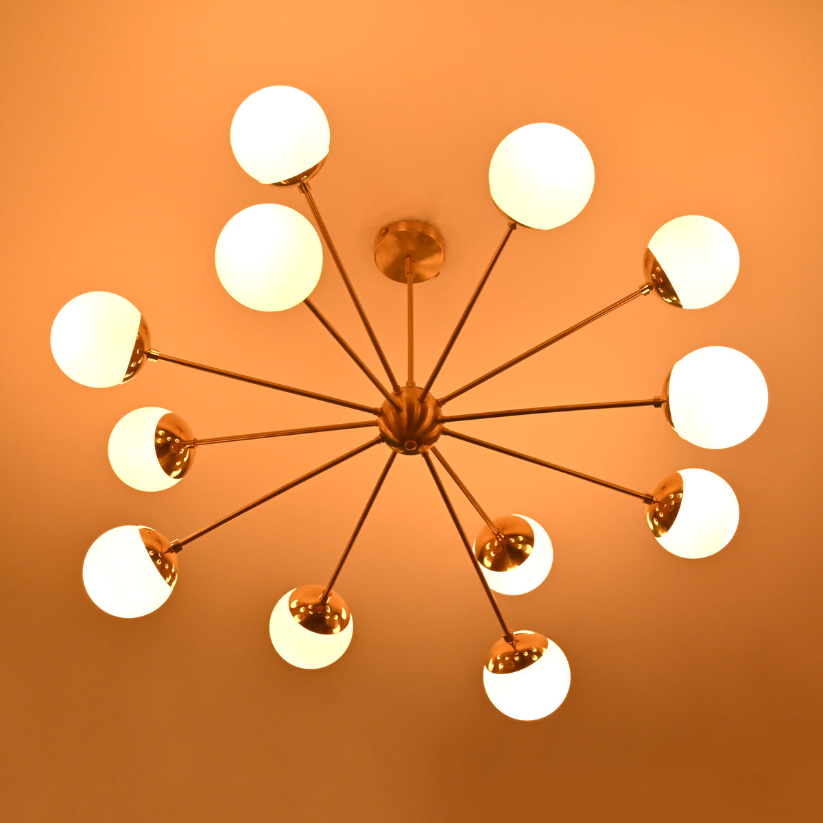 Modern brass chandelier with glowing opal globes creating dramatic evening ambience