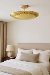 Modern brass disc flush mount ceiling light providing warm ambient lighting in a bedroom