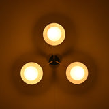 Brass disc flush mount ceiling light glowing warmly in a dark interior, highlighting opal glass globes.