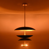 Modern brass disc chandelier casting upward indirect light, creating a warm ceiling wash effect