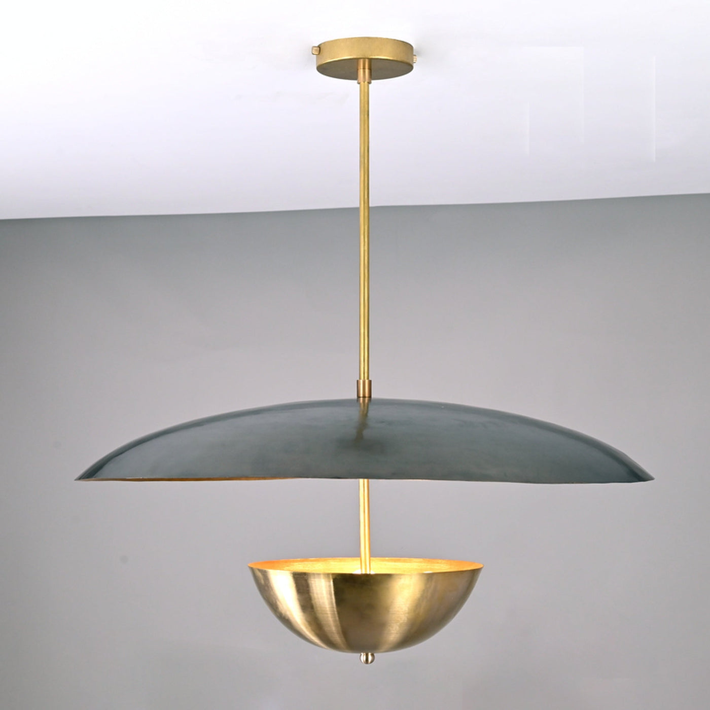 Front view of modern brass dual-shade pendant featuring a wide dome and inner brass bowl in a sculptural contemporary design.