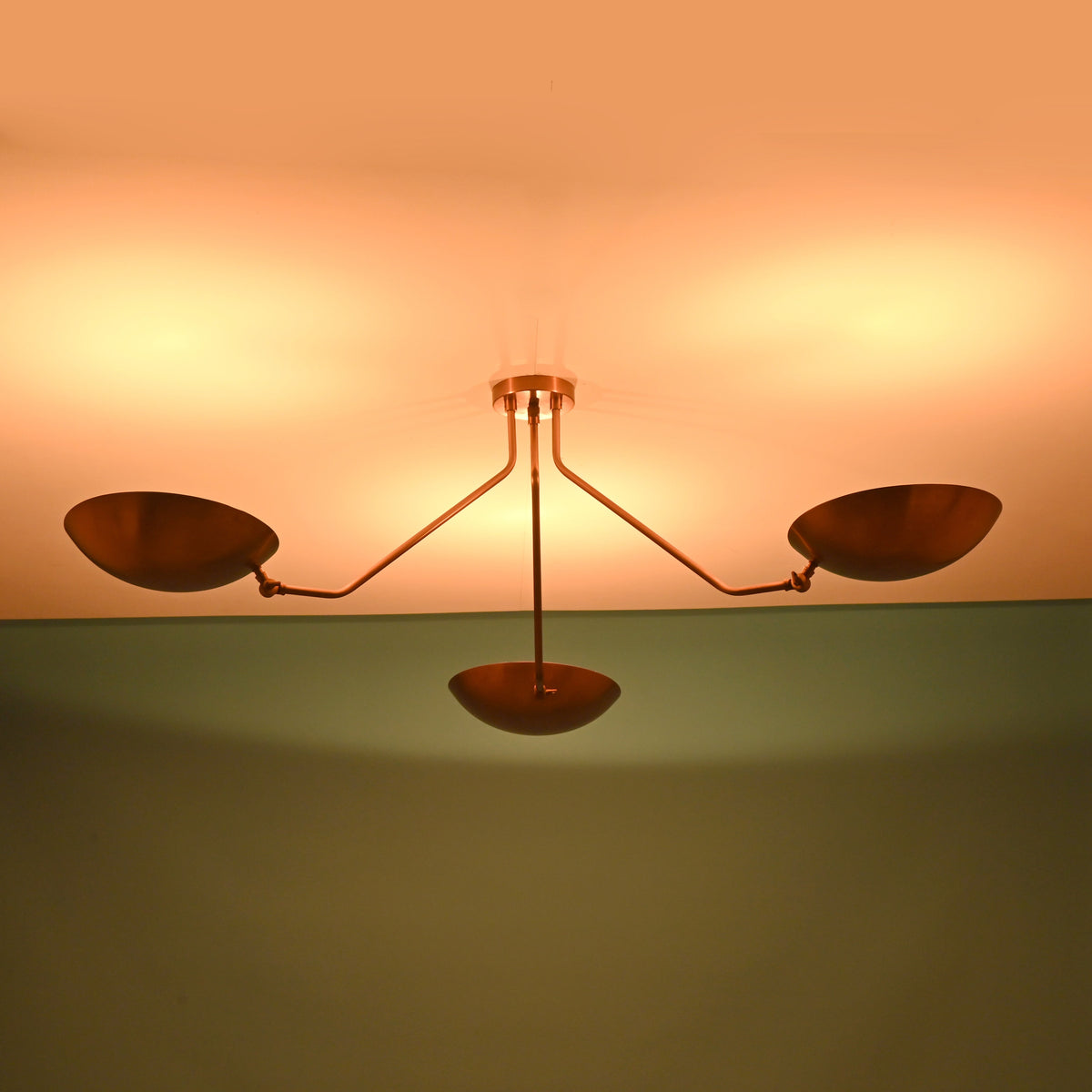 Modern brass flush mount ceiling light with bowl shades creating symmetrical ambient illumination across the ceiling