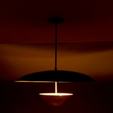 Evening profile view of modern brass pendant with dual shades producing soft, diffused ambient lighting.
