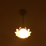 Modern brass pendant light with scalloped shade producing gentle side glow at night.