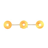 Modern brass wall light closeup showing rounded reflectors and warm bulb glow for boutique interior styling
