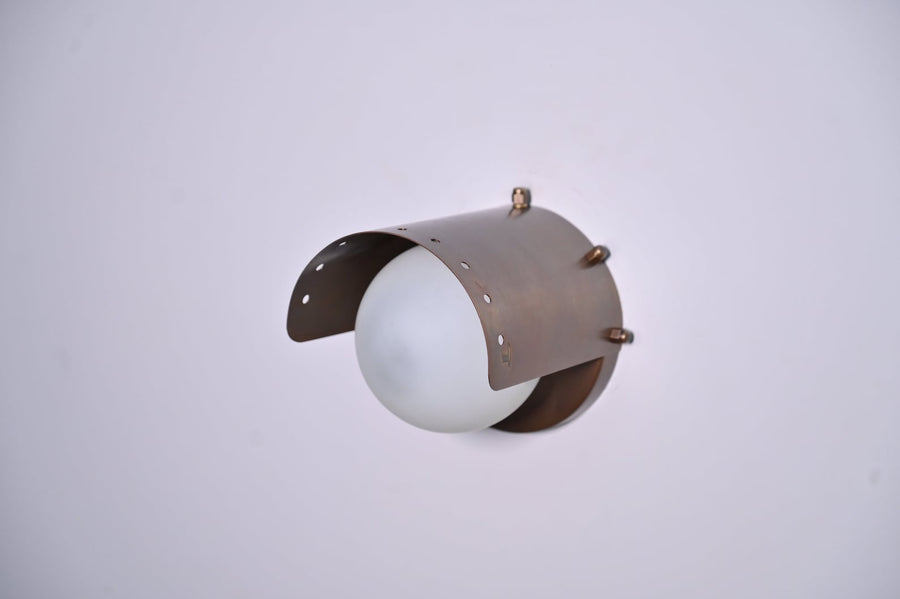 Handcrafted industrial brass wall light with curved brushed brass shade and glowing globe by Brass Leaf Studio