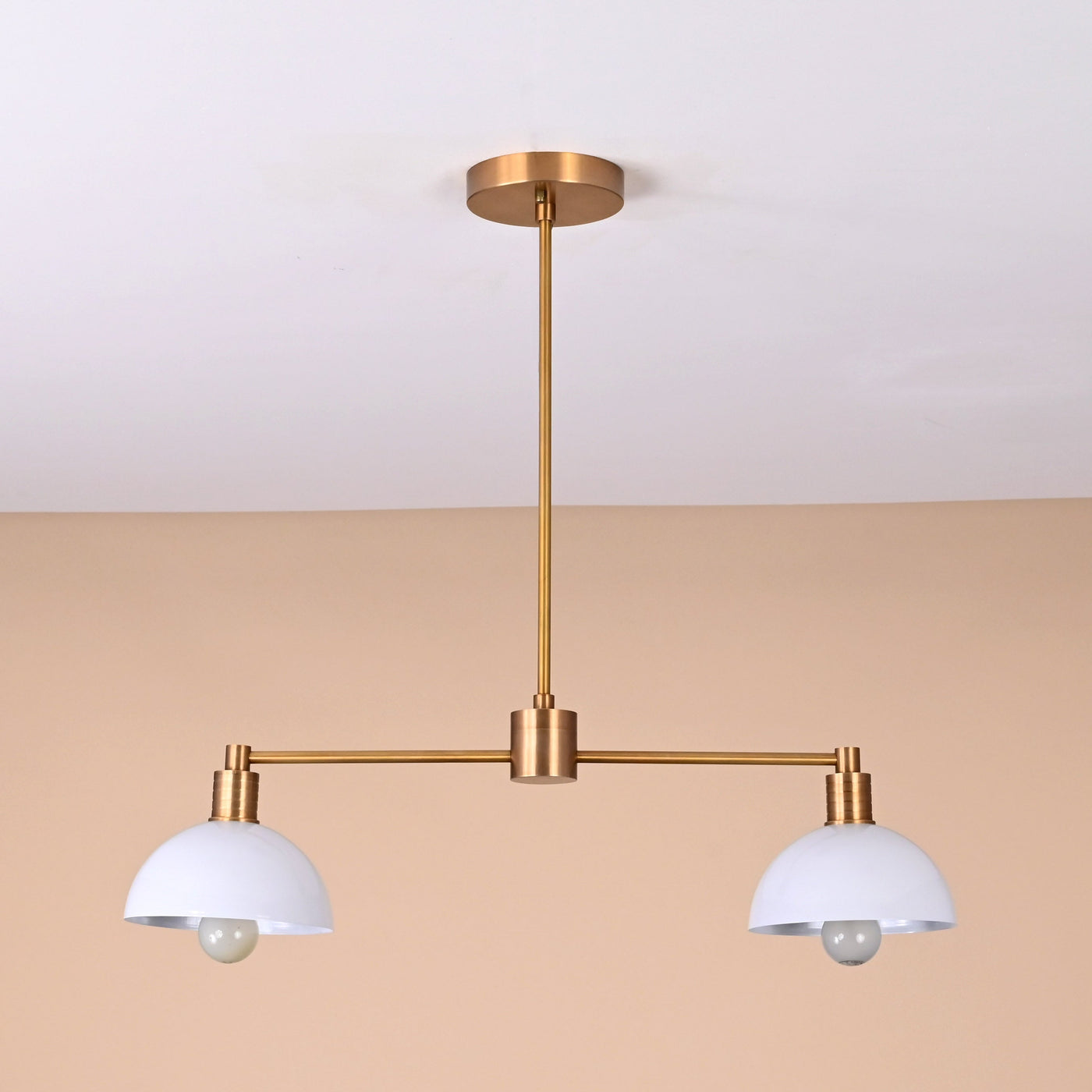 Modern two-light brass pendant with white domed shades and sleek minimalist design