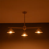 Handcrafted brass cone chandelier with three lights glowing softly in ambient warm lighting.