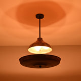 Modern copper disc chandelier suspended from ceiling, glowing softly in a dark ambient setting