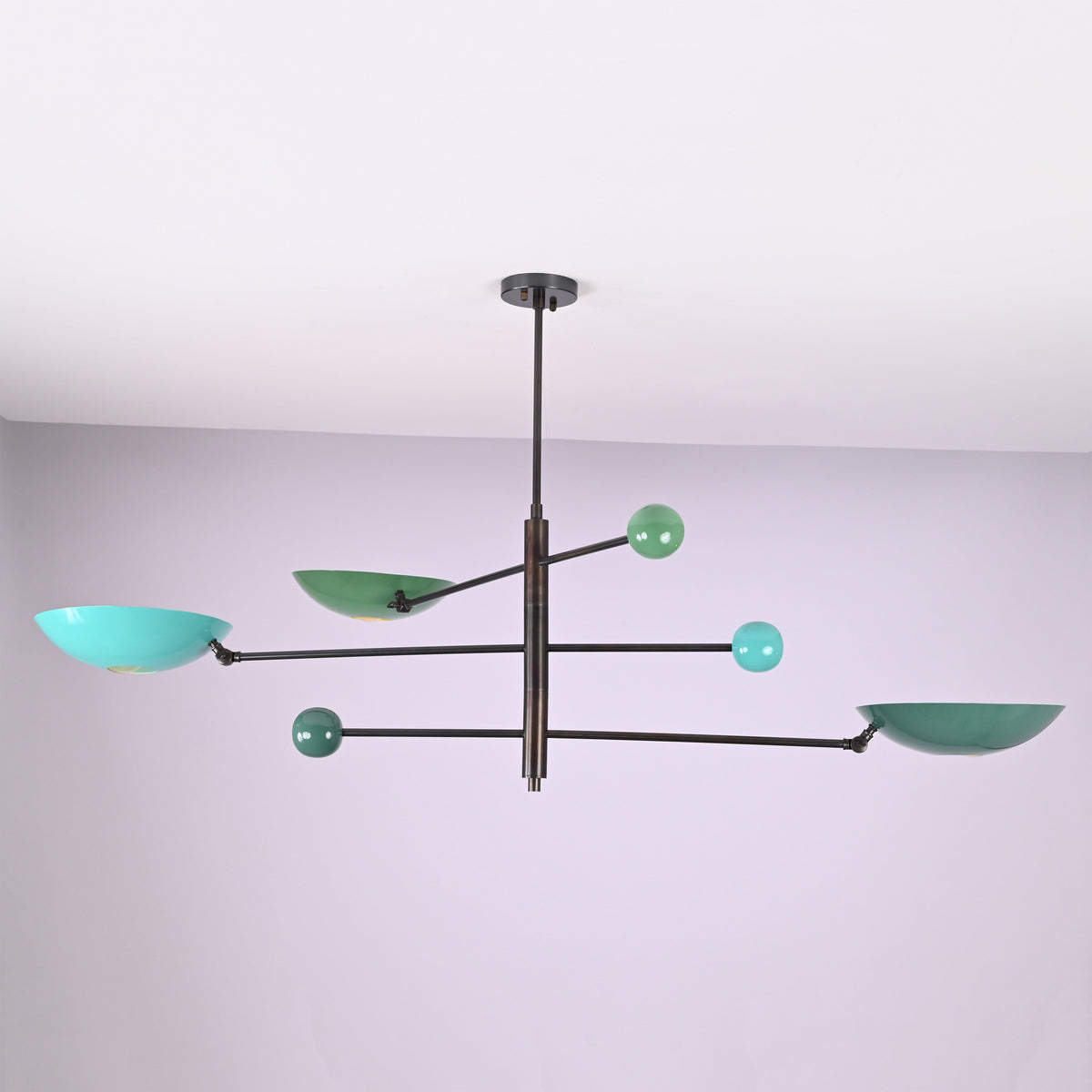 Modern brass disc chandelier with extended arms and colored shades viewed from an angled perspective