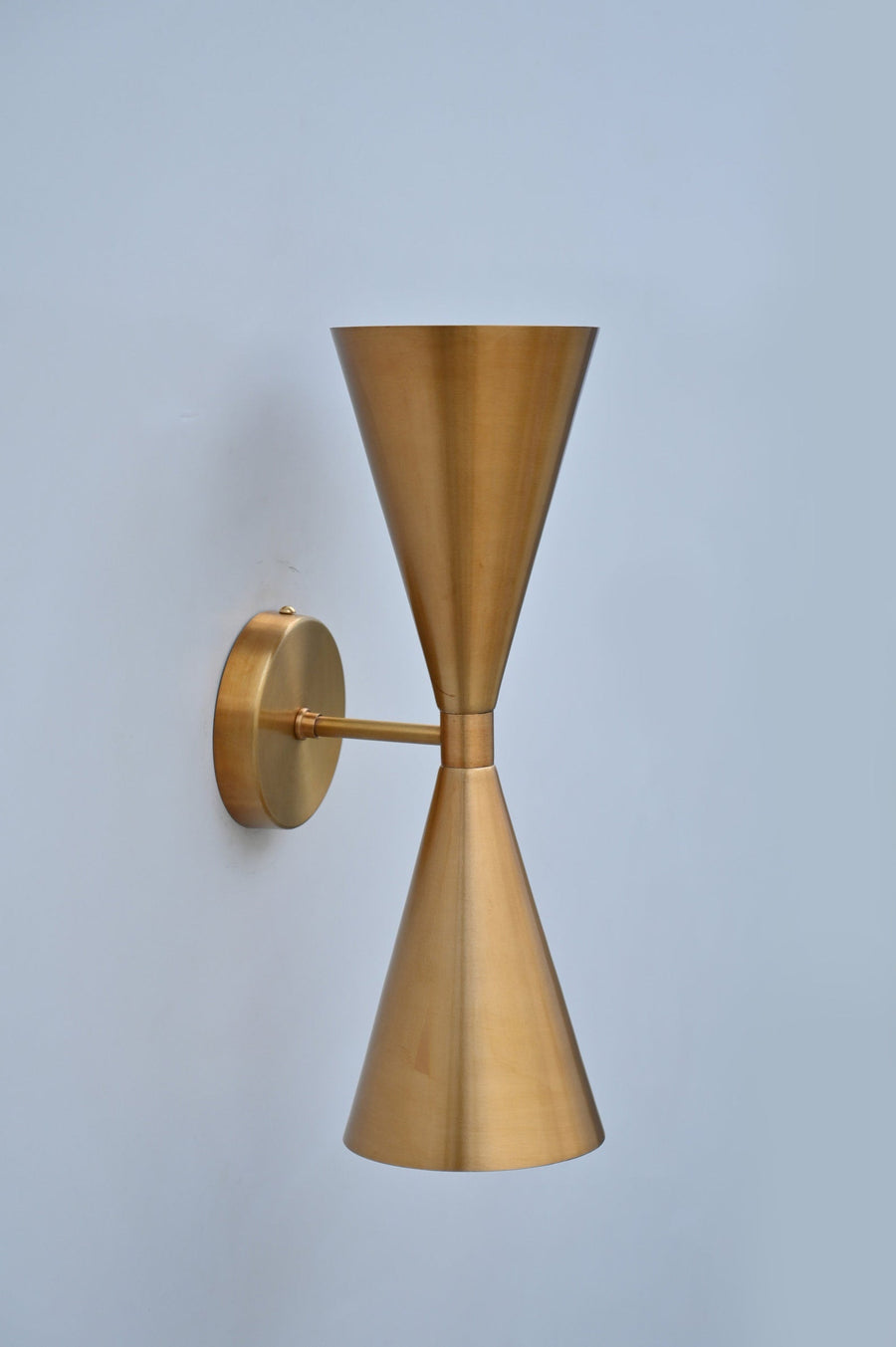 Front view of double cone wall light in brushed brass finish, handcrafted solid brass sconce with symmetrical up-and-down design.