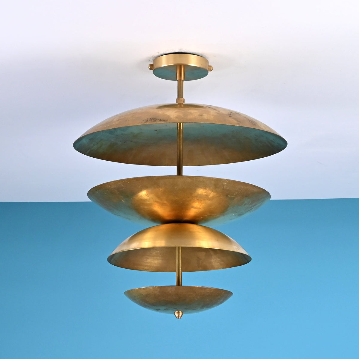 Sculptural layered brass ceiling light featuring stacked bowl-shaped discs in a modern industrial flush mount profile.