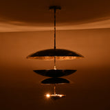 Modern multi-tier brass disc chandelier producing warm indirect light and sculptural glow