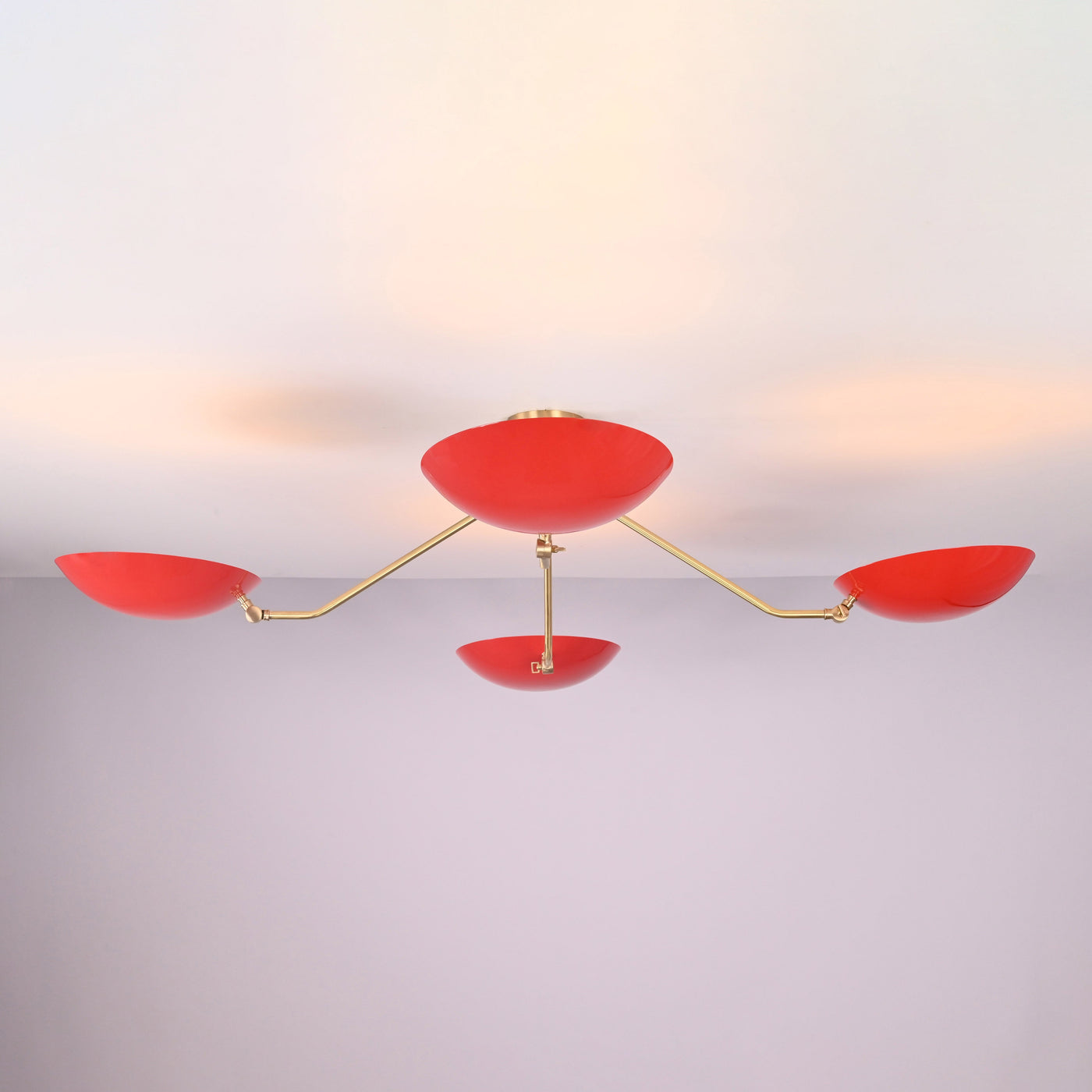 Angled view of modern red disc chandelier highlighting solid brass craftsmanship and minimalist industrial design.