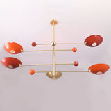 Modern sculptural chandelier in brushed brass with red bowl shades providing upward indirect lighting.