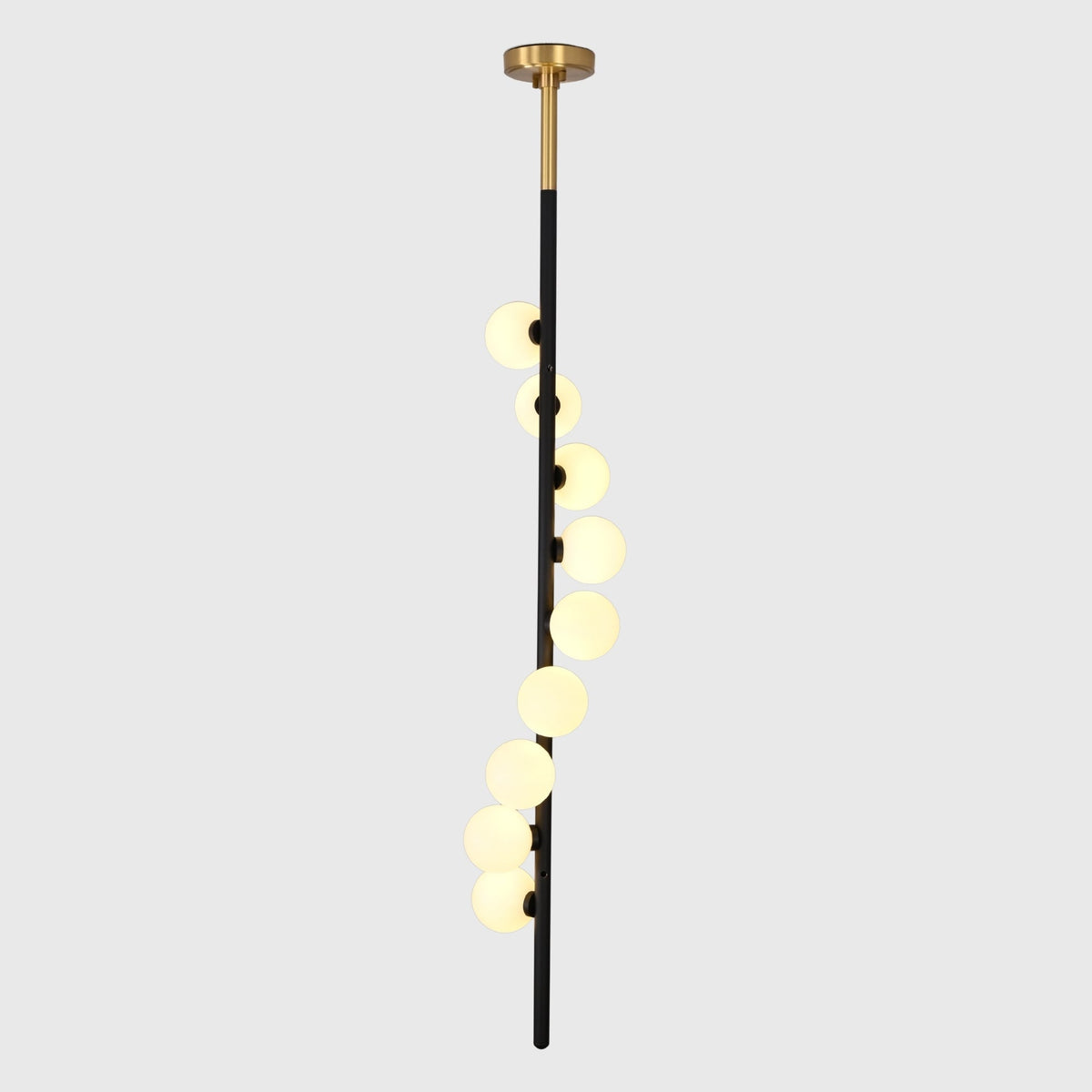 Modern stairwell globe chandelier shown from side angle with staggered round shades and tall vertical profile