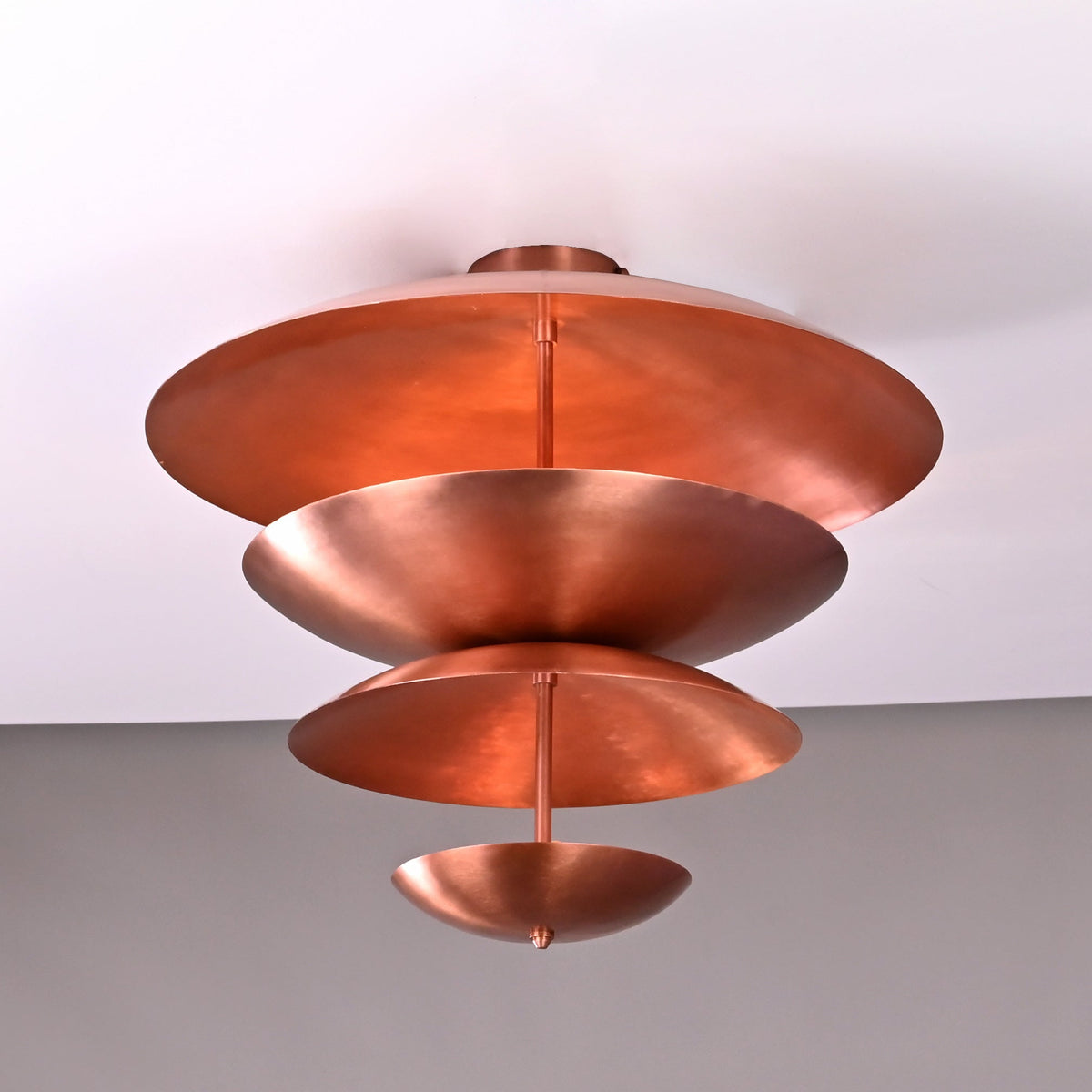 Bottom-angle shot of the modern tiered brass flushmount chandelier showcasing its sculptural bowl geometry and polished copper finish.