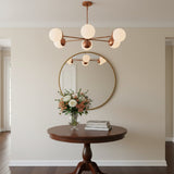 Monaco brass globe chandelier shown illuminated with warm ambient lighting and six glowing glass shades
