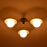 Night view of 3 light brass disc ceiling fixture with opal glass globes creating ambient lighting.